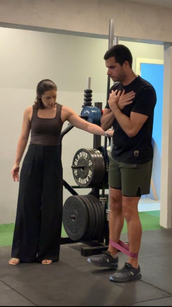 Dra. Escarllet Alves orientando um paciente em um exercício de equilíbrio com faixa elástica